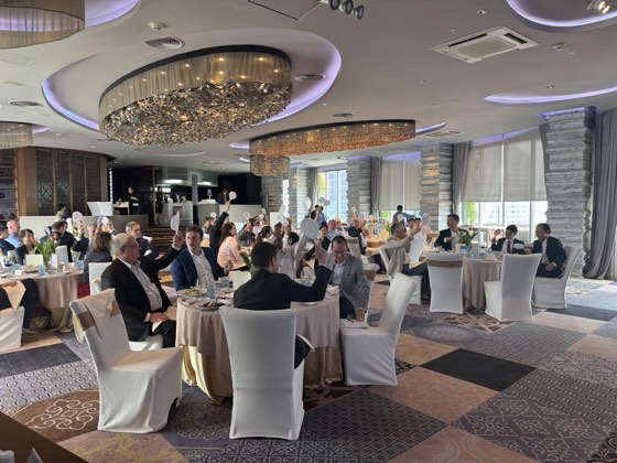Members at tables under a chandelier