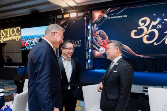 Three guests in evening dress talking beside the stage screen