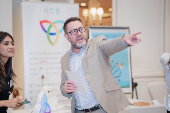 An exhibitor pointing across the hall