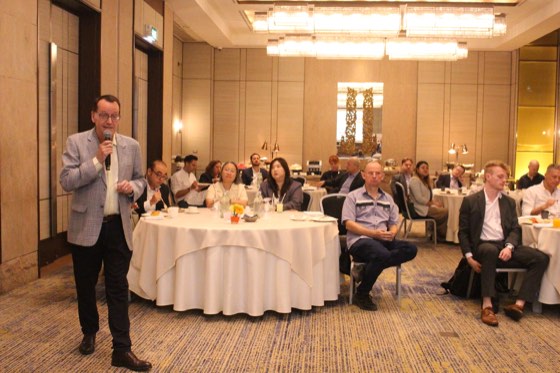 A speaker with a microphone addressing a breakfast audience